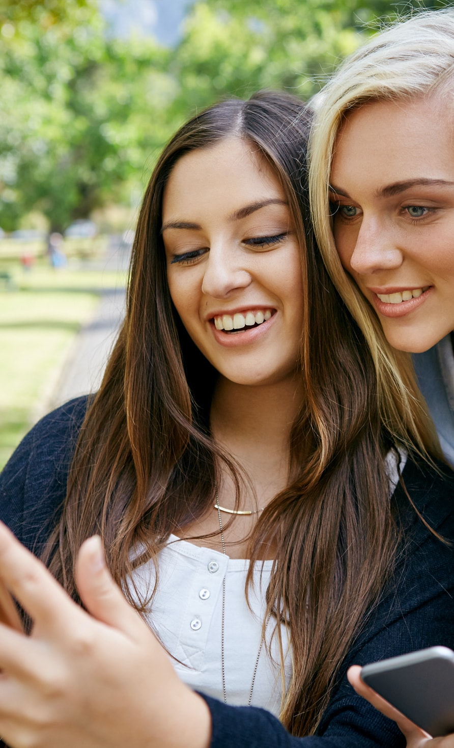 Two young women with cell phones in their hands looking for jobs at Frutura
